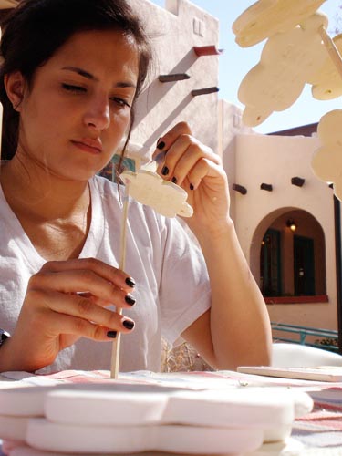 Maria Fallon paints a clay flower at Bens Bells, a nonprofit organization in Tucson. The organization relies heavily on volunteers to help create the ceramic bells they hang around the city.