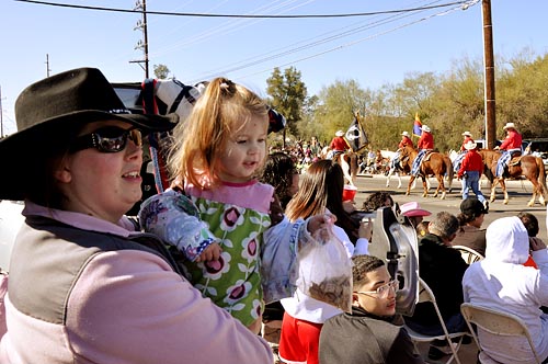 Luann Read and her daughter Lavita, 1, try to catch a glimpse of the parade at the 85th La Fiesta de los Vaqueros Rodeo Parade. Reed joined thousands of Tucsonans the shortened parade route.